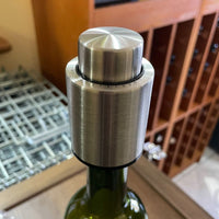 Tapón metálico con bomba integrada colocado sobre botella estándar.